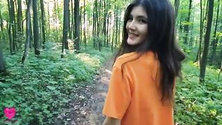 A girl is checking her figure while walking in the forest
