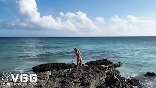 A sexy girl is completely naked on the beach, showcasing her petite frame and small tits in a daring solo display