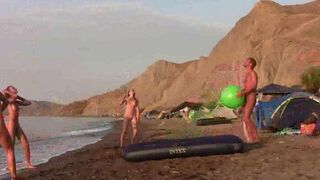 A naked girl is having fun playing badminton on the beach