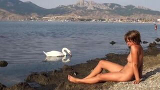 A naked girl is having fun on the riverbank, just like in similar outdoor nudity videos