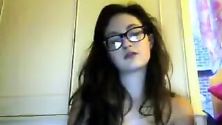 A cute student with glasses gets undressed during a video chat