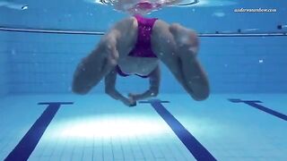 A hot naked girl is swimming in the pool under the jets