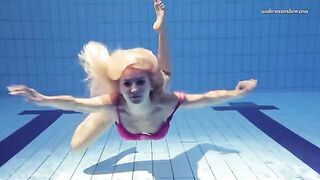 A hot naked girl is swimming in the pool under the jets