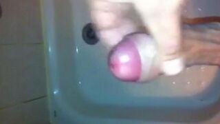 The kid caresses his dick under the stream of water in the shower