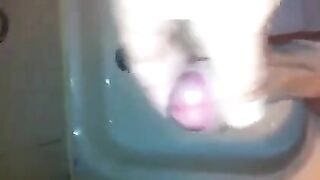 The kid caresses his dick under the stream of water in the shower