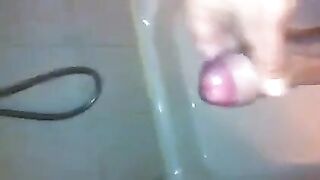 The kid caresses his dick under the stream of water in the shower