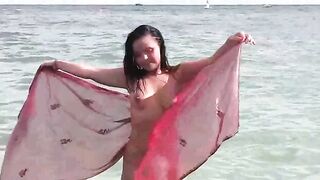 A naked girl bathes in the sea, using her hands to caress her body