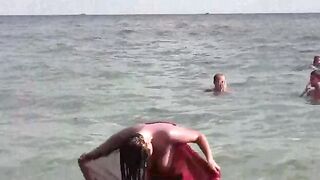 A naked girl bathes in the sea, using her hands to caress her body