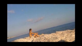 A hot young girl is basking in the sun naked on the beach