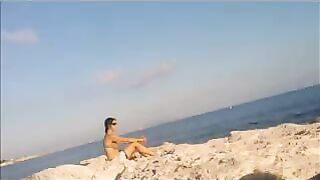 A hot young girl is basking in the sun naked on the beach