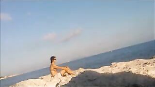 A hot young girl is basking in the sun naked on the beach