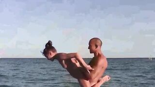 A group of naked gymnastics enthusiasts have a lot of fun on the beach